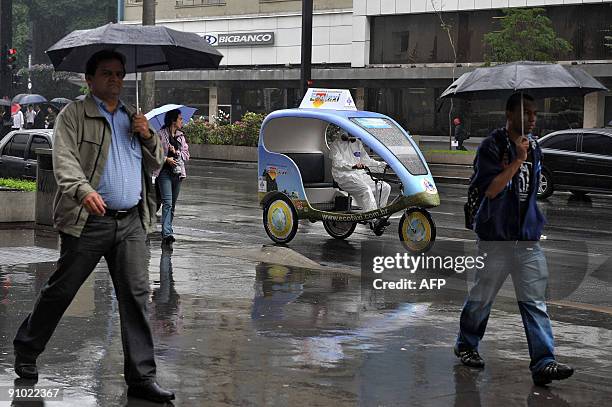 An activist rides a prototype taxi, called 'EcoTaxi', a covered three-wheel bicycle free of all carbon emissions, through the financial district of...