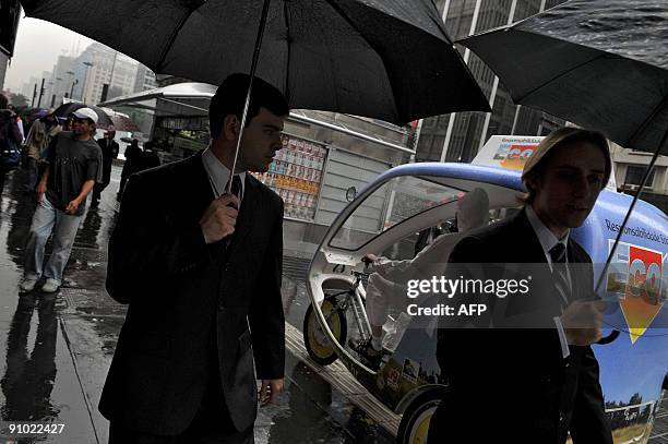 People walk past an activist riding on a prototype taxi, called 'EcoTaxi', a covered three-wheel bicycle free of all carbon emissions, through the...