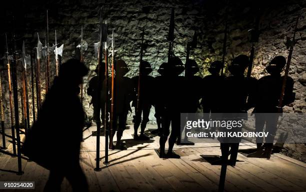 Woman walks past figures of medieval knight silhouettes inside the watchtower of the Chateau De Chillon in Montreux on January 25, 2018. / AFP PHOTO...