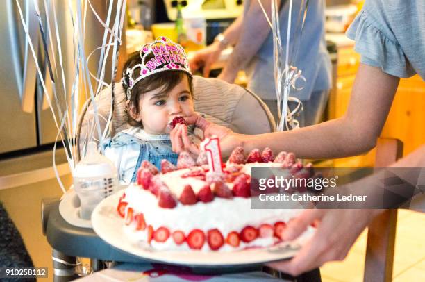1 year old eating strawberry from birthday cake - eerste verjaardag stockfoto's en -beelden