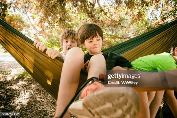 playful children in a hammock swing together - kicking tire stock pictures, royalty-free photos & images