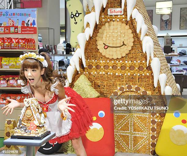 Japanese model Aki Hoshino displays a small replica and the 2.1m tall sweet house, decorated with cookies and sugar candies for the sales promotion...