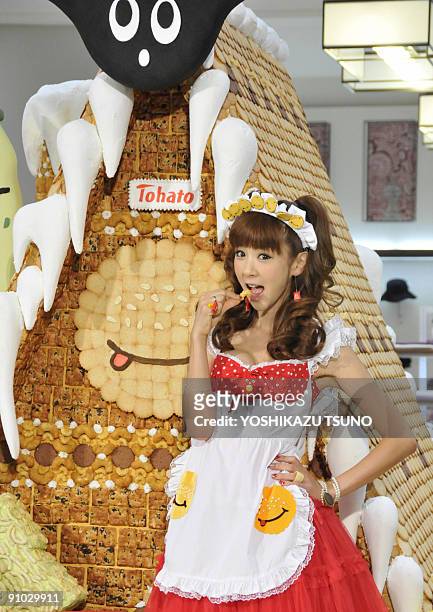 Japanese model Aki Hoshino displays a piece of cookie before the 2.1m tall sweet house, decorated with cookies and sugar candies for the sales...