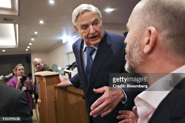 George Soros, billionaire and founder of Soros Fund Management LLC, speaks to an attendee on day three of the World Economic Forum in Davos,...