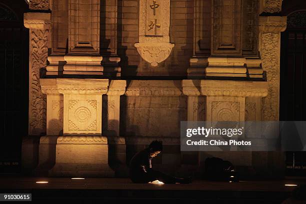 Senior citizen sits on the ground and reads through the in-ground light outside the Wangfujing Church on September 22, 2009 in Beijing, China....