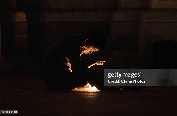Senior citizen sits on the ground and reads through the in-ground light outside the Wangfujing Church on September 22, 2009 in Beijing, China....