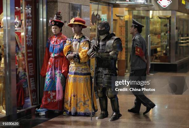 Sales staffs dressed as the Qing Dynasty empress, emperor and a knight, stand in front of a shop to attract customers at the Wangfujing Pedestrian...