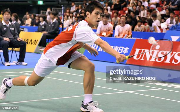 Japan's Kenichi Tago reaches for a return against Ng Wei of Hong Kong during their men's singles first round match at the Japan Open badminton...