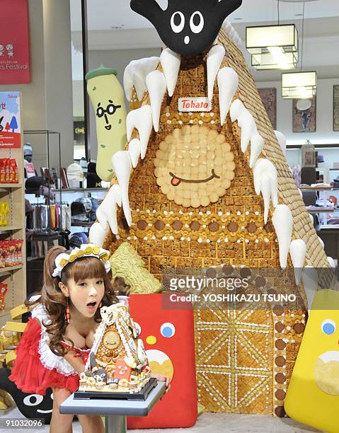 Japanese model Aki Hoshino displays a small replica and the 2.1m tall sweet house, decorated with cookies and sugar candies for the sales promotion...