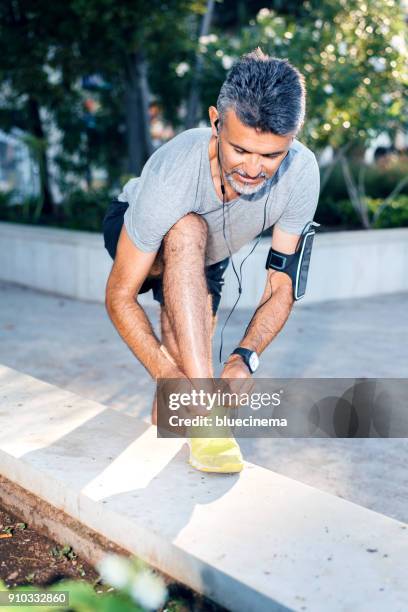 runner man lacing shoes - running spikes stock pictures, royalty-free photos & images