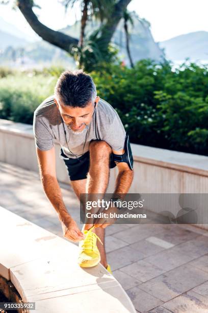 runner man lacing shoes - running spikes stock pictures, royalty-free photos & images