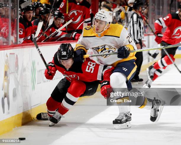 Kevin Rooney of the New Jersey Devils is hit by Alexei Emelin of the Nashville Predators in the second period on January 25, 2018 at Prudential...