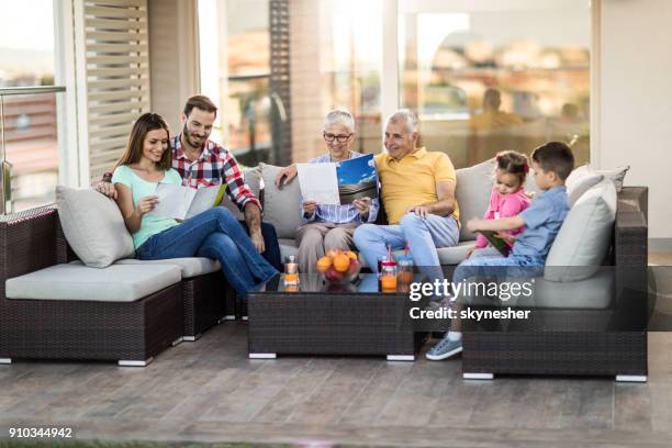 happy extended family relaxing on sofa at penthouse patio. - penthouse girl stock pictures, royalty-free photos & images