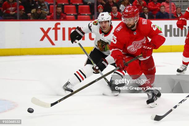 Mike Green of the Detroit Red Wings tries to control the puck in front of Brandon Saad of the Chicago Blackhawks during the third period at Little...