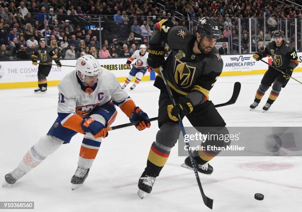 Jason Garrison of the Vegas Golden Knights skates with the puck under pressure from John Tavares of the New York Islanders in the first period of...