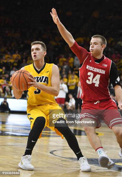 Iowa guard Jordan Bohannon tries to pass the b all while guarded bye Wisconsin Badgers guard Brad Davidson during a Big Ten Conference basketball...