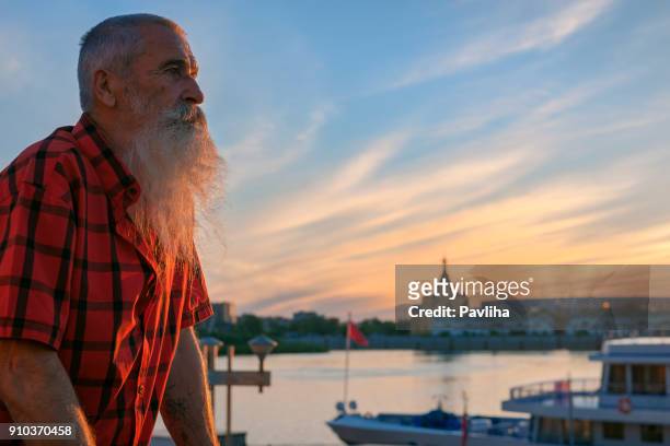 porträt-senior-mann mit weißen bart auf eine reise durch die russischen flüsse, sonnenuntergang - volga stock-fotos und bilder