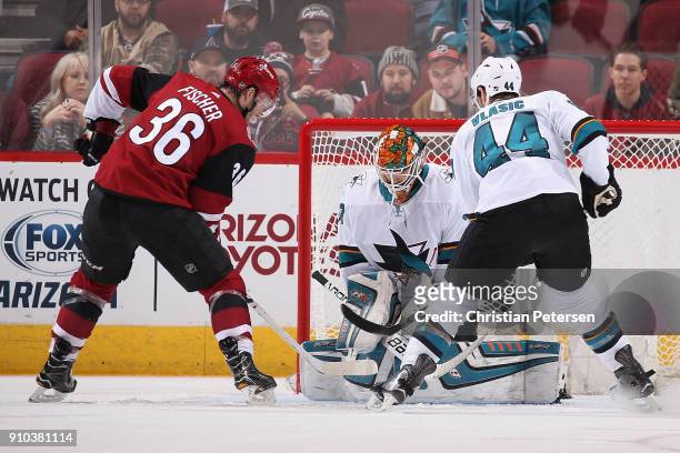 Goaltender Aaron Dell of the San Jose Sharks makes a save on Christian Fischer of the Arizona Coyotes during the third period of the NHL game at Gila...