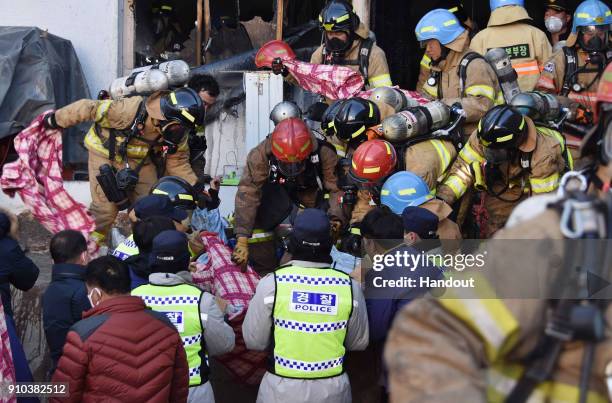 In this handout picture provided by the Kim Gu Yeon-Gyeongnam Domin Ilbo, Rescue workers remove bodies from a hospital fire on January 26, 2018 in...