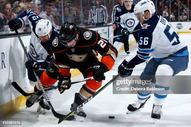 Chris Wagner of the Anaheim Ducks battles for the puck against Matt Hendricks and Marko Dano of the Winnipeg Jets during the game on January 25, 2018...