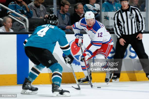 Peter Holland of the New York Rangers keeps the puck away from Brenden Dillon of the San Jose Sharks at SAP Center on January 25, 2018 in San Jose,...
