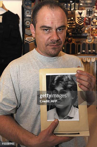 Former German shot putter Andreas Krieger, who competed as a woman on the East German athletics team, poses with a picture of himself in 1987 during...