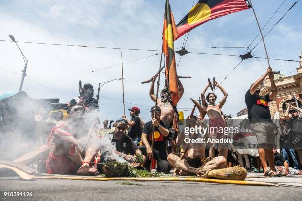 Group of Aboriginal men sitting in at an intersection waving Aboriginal flags and playing with traditional instruments during a protest by Aboriginal...