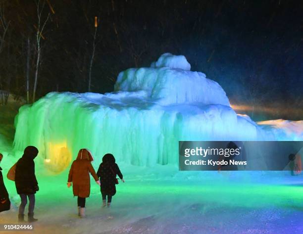Visitors approach an ice sculpture lit up at the annual ice festival held at the Sounkyo hot spring resort in Kamikawa in the northernmost Japanese...