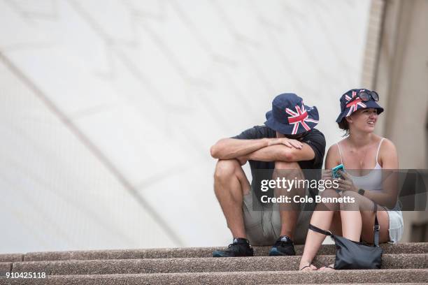 Couple wearing matching Australia Day hats wait out the heat on the steps of the Opera House on January 26, 2018 in Sydney, Australia. Australia Day,...