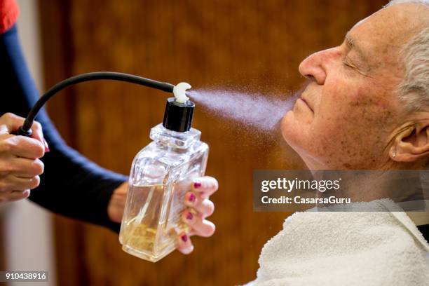 barber spraying aftershave on senior man - man spraying stock pictures, royalty-free photos & images