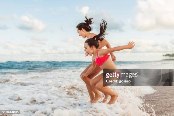 duas irmãs irmão feliz, saltando sobre as ondas - beach - fotografias e filmes do acervo