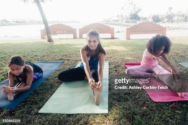 three schoolgirls practicing yoga pose on school sports field - teenager yoga stock pictures, royalty-free photos & images