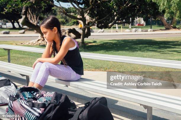 schoolgirl soccer player alone on bench on school sports field - fille maillot photos et images de collection