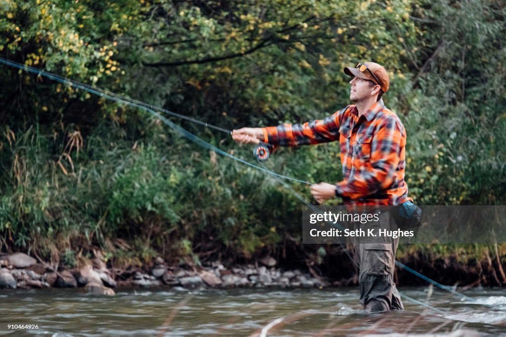 Man wading in river, fishing