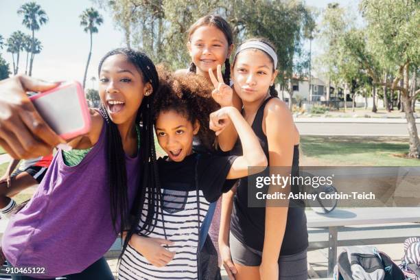 schoolgirl soccer players taking smartphone selfie on school sports field - 10 to 13 years stock pictures, royalty-free photos & images