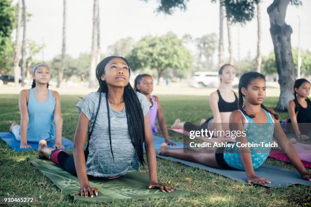 girls and teenage schoolgirls practicing yoga upward facing dog on school playing field - 10 to 13 years stock pictures, royalty-free photos & images