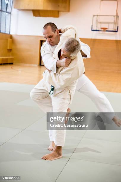 senior judoist versucht, den gegner zu boden zu werfen - takedown stock-fotos und bilder