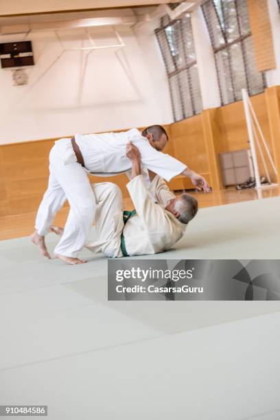 senior judoist mittels judo technik, um seine gegner auf ihn zu werfen - takedown stock-fotos und bilder