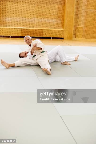 senior judoist seinen gegner zu boden zu zwingen - takedown stock-fotos und bilder
