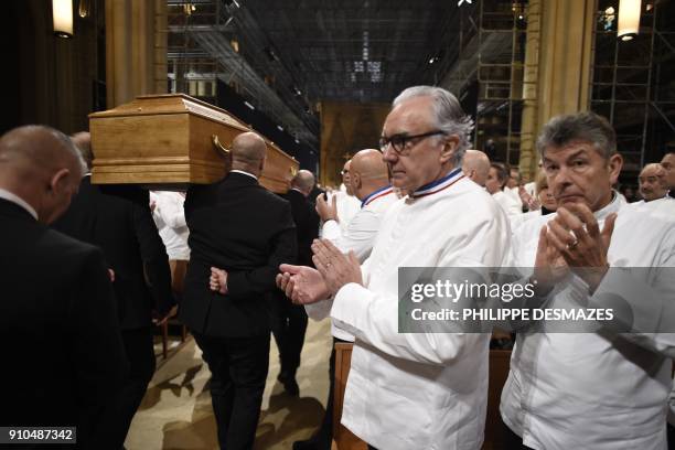 French chefs Alain Ducasse and Regis Marcon applaud as the coffin French chef Paul Bocuse leaves the Saint-Jean Cathedral in Lyon on January 26, 2018...
