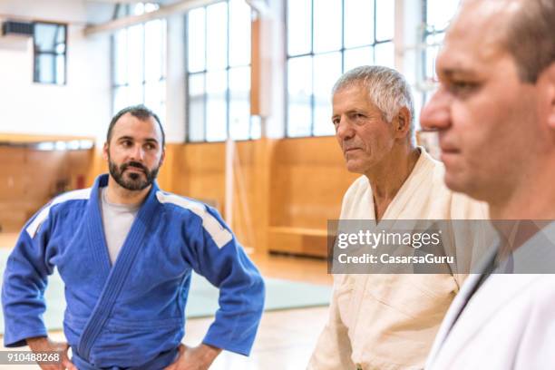 tres personas en kimono permanente y socializar - mens judo fotografías e imágenes de stock
