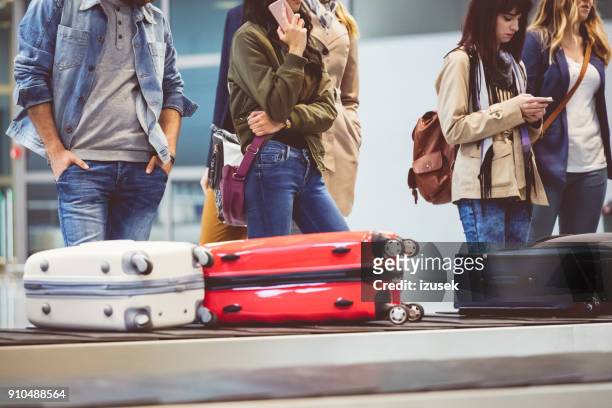 airplane travelers waiting for luggage near conveyor belt - baggage claim imagens e fotografias de stock
