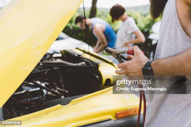 young adults on road trip using jump leads to start vehicle - jumper cable stock pictures, royalty-free photos & images