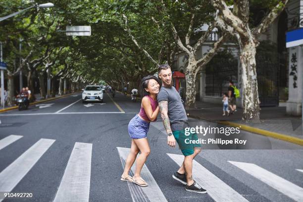 woman pushing boyfriend on pedestrian crossing, shanghai french concession, shanghai, china - pierced stock pictures, royalty-free photos & images