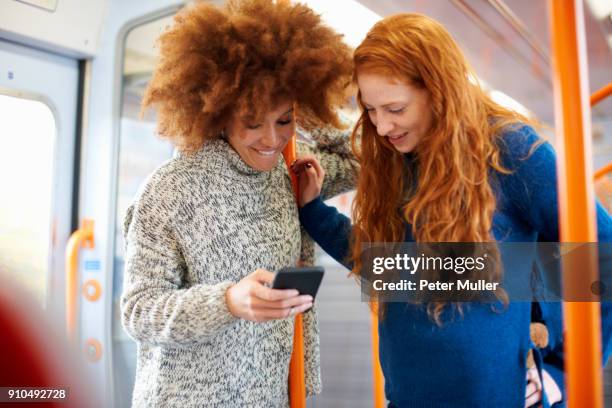 friends sharing message on mobile phone on train, london - england training session stock pictures, royalty-free photos & images