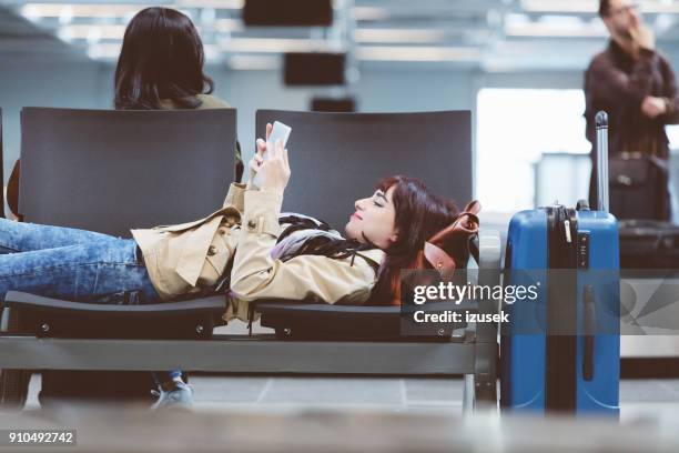 mooie vrouw te wachten voor de vertraagde vlucht in luchthaven lounge - jet lag stockfoto's en -beelden