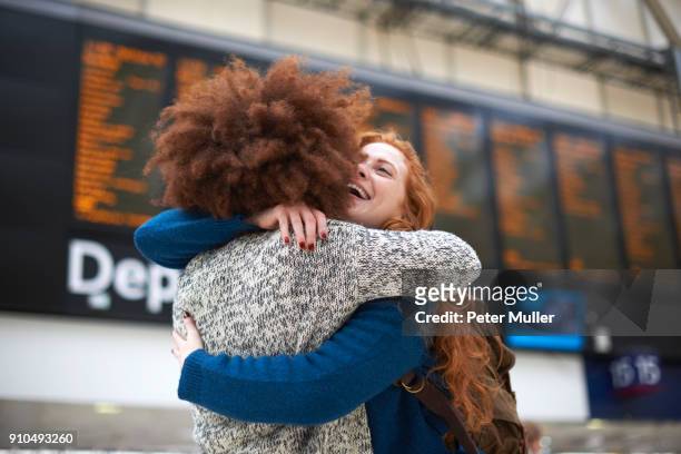 two young women hugging at train station - railroad station stock pictures, royalty-free photos & images