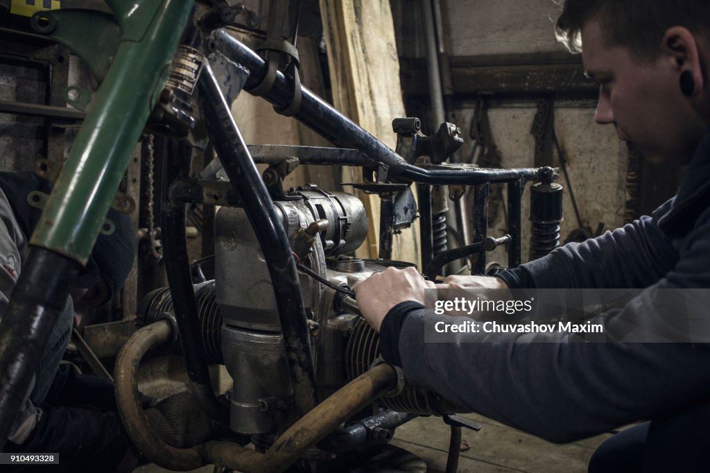 Mechanic repairing vintage motorcycle engine in workshop