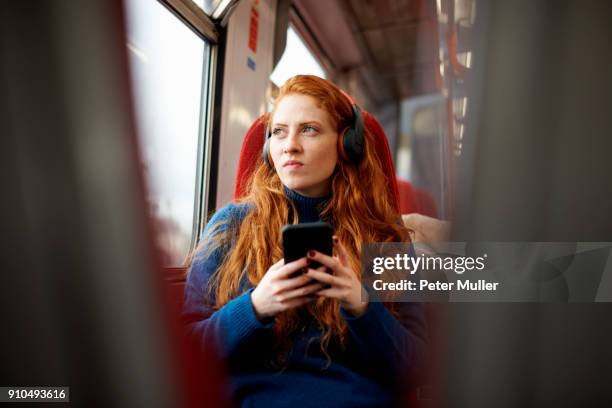 woman on train listening to music on mobile phone with headphones, london - headphones woman stock pictures, royalty-free photos & images