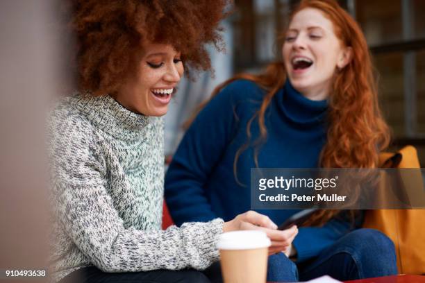 friends at coffee shop using mobile phone laughing - gossip stock pictures, royalty-free photos & images